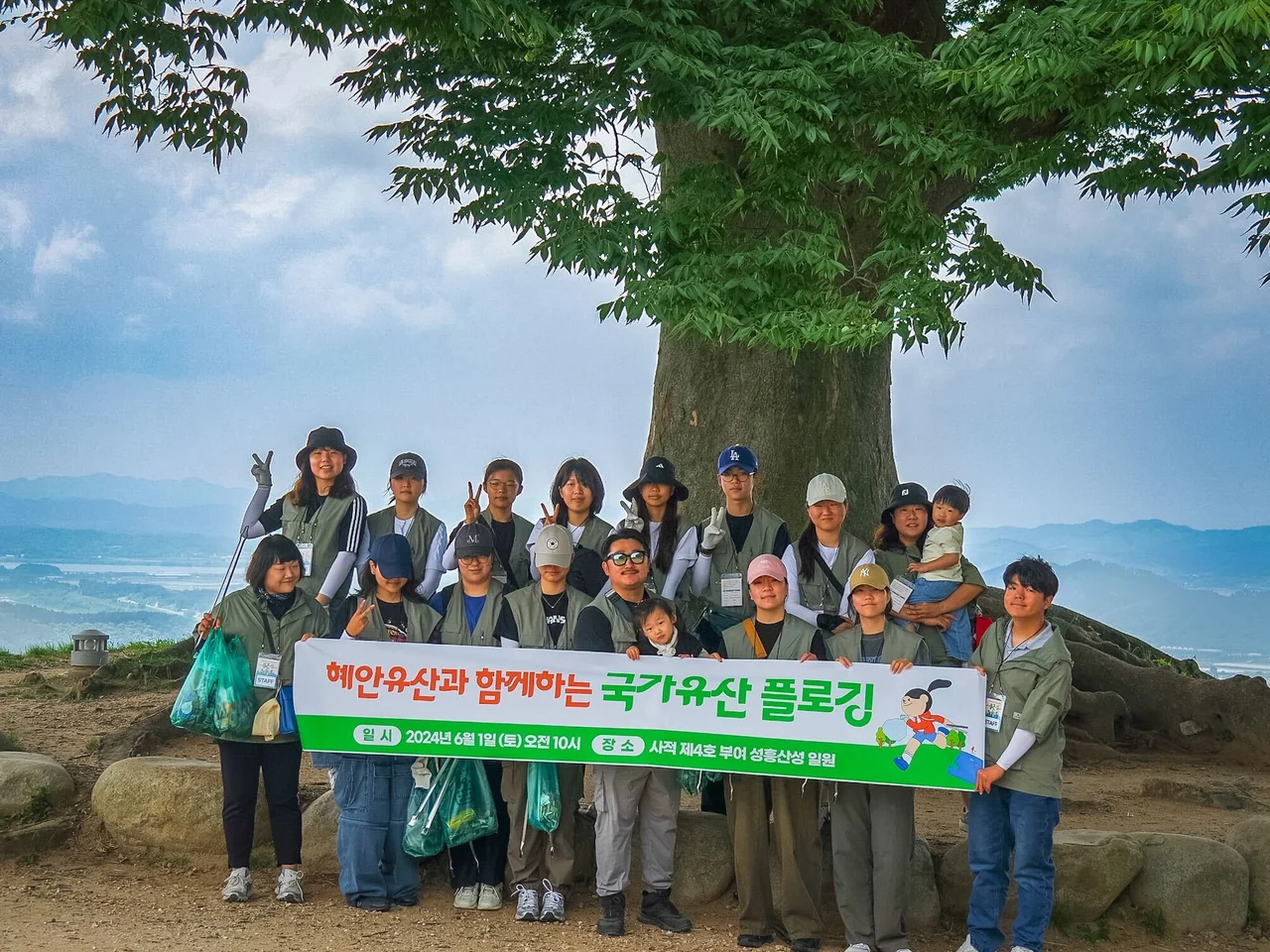 성흥산성 사랑나무 앞에서 플로깅 현수막과 수거 봉투를 든 참가자들