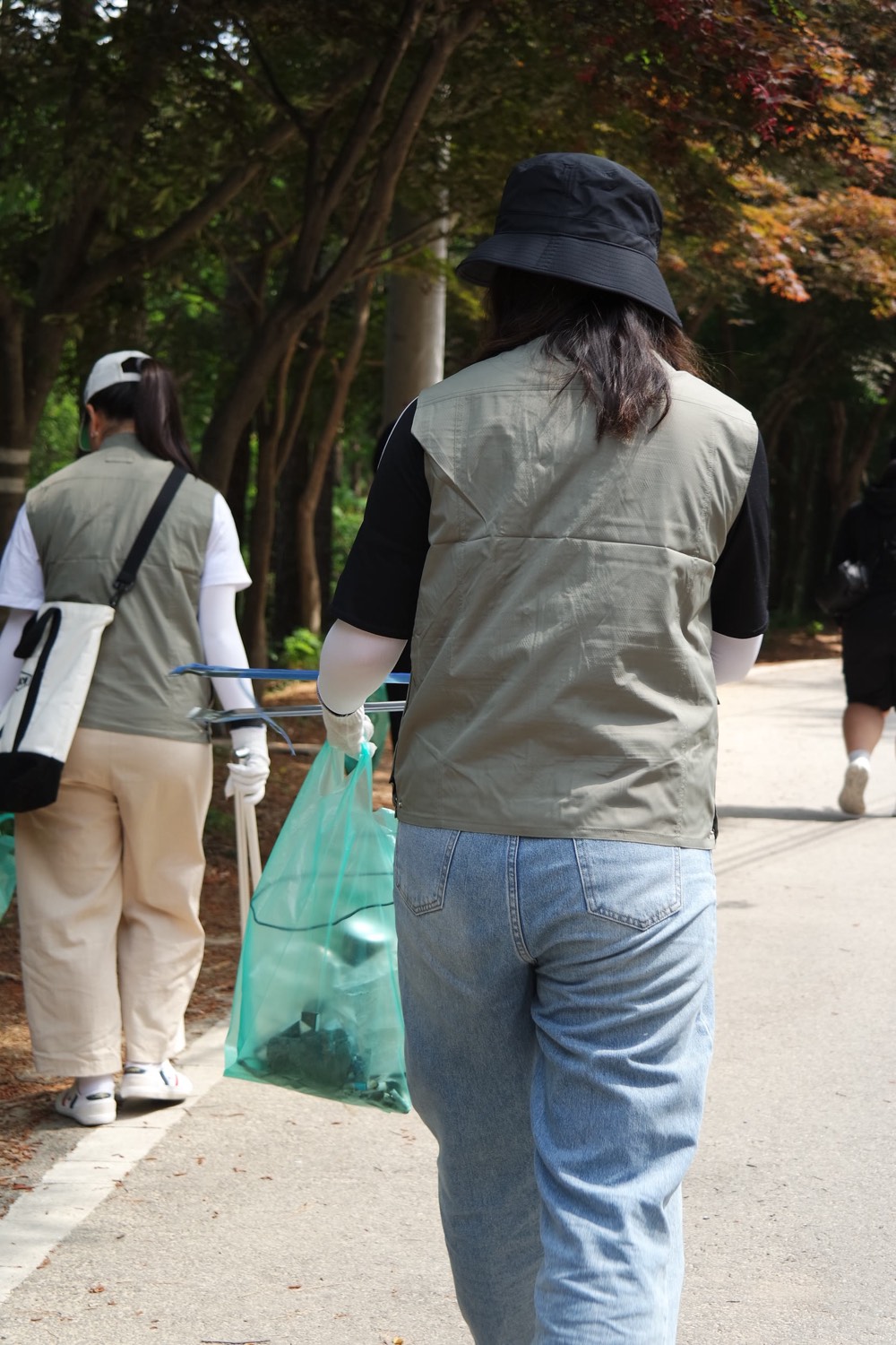 숲길을 걸으며 플로깅하는 참가자들의 뒷모습